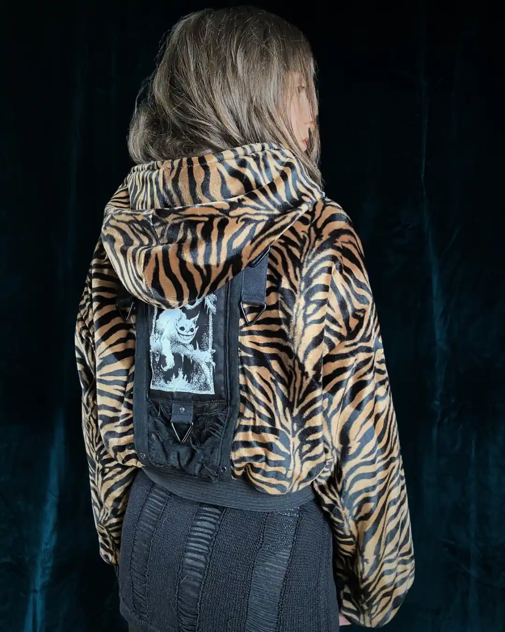 Vegane Tigerfell-Jacke mit schwarz-goldenem Streifenmuster, breitem Bund und einzigartigem Rücken-Patch, Nieten, Metallringen und Mesheinsatz – ideal für Darkwear-Looks und Clubstyles.