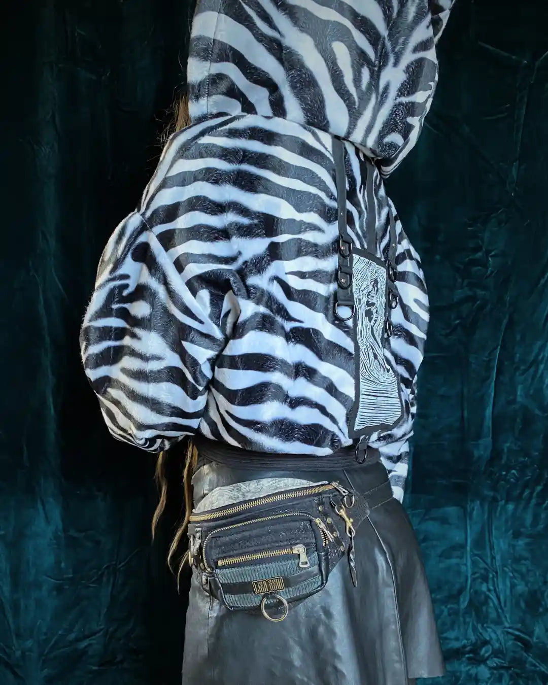 Vegane Zebrafell-Jacke mit weiß-schwarzem Muster, Kapuze und markantem Rücken-Patch – ideal für Ravewear und Clubfashion.